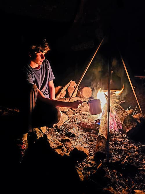 A person holding a pan above a fire