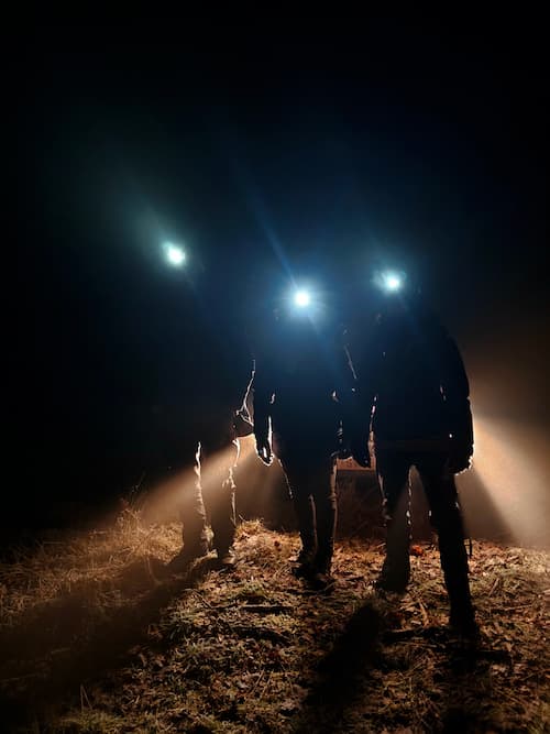 Night navigation exercise with headlamps during wilderness survival training.