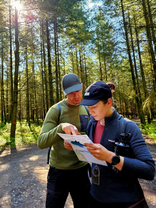 2 personen in het bos, lezend op een kaart